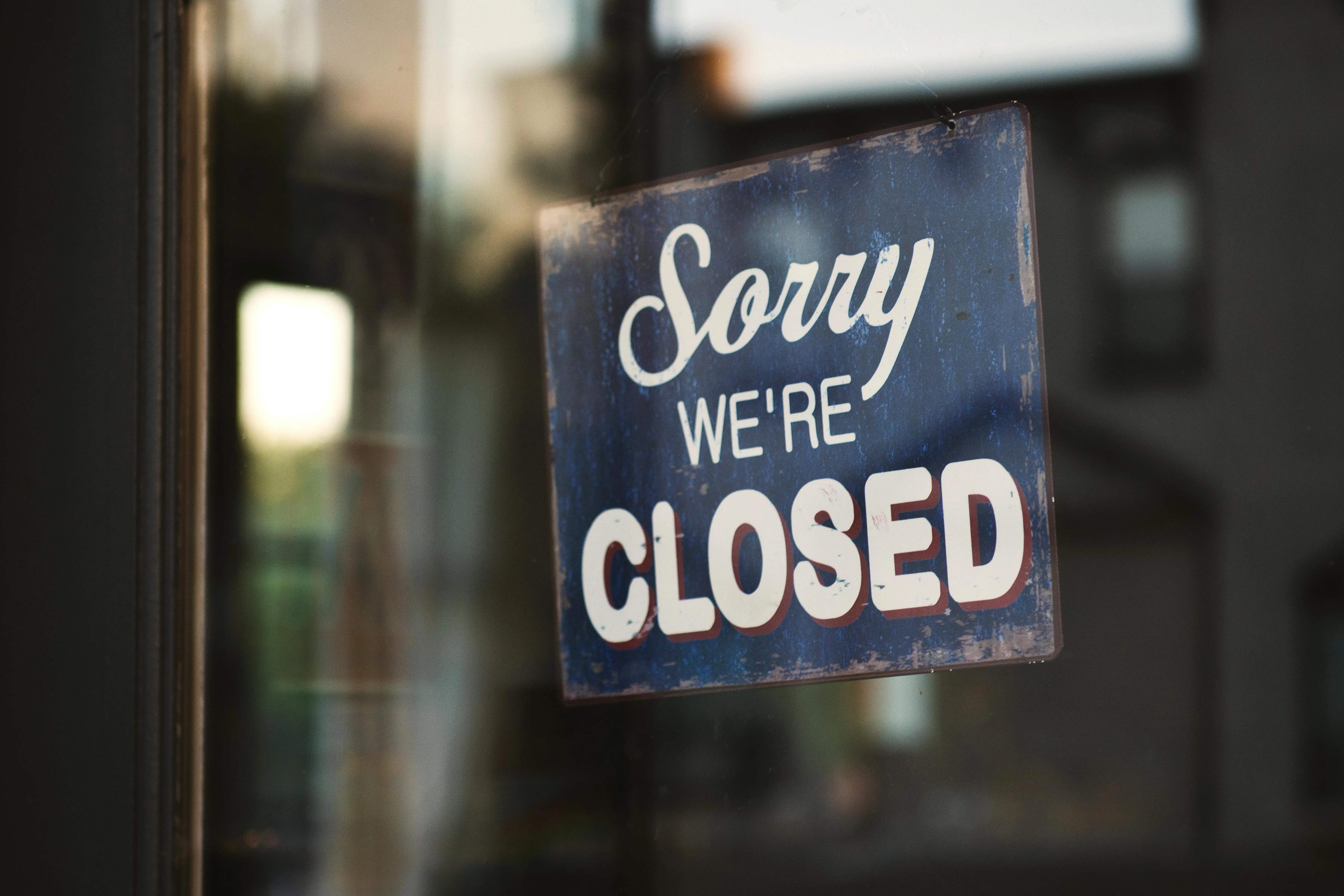 Sorry We're Closed' sign on a storefront window, symbolizing the permanent closure and dissolution of a business entity.