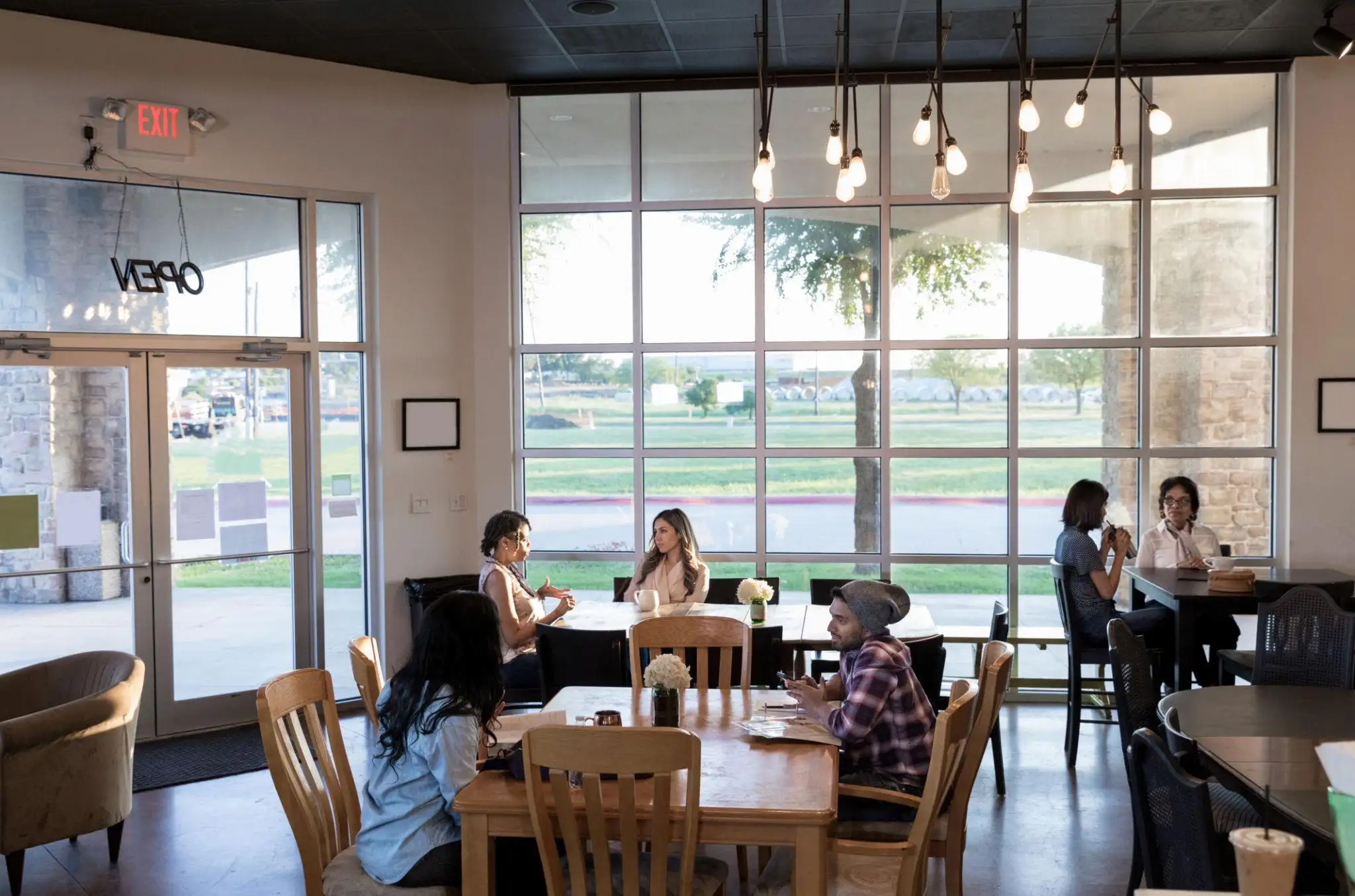 Two people reviewing paperwork at a table in a bright cafe, discussing a DBA vs LLC.