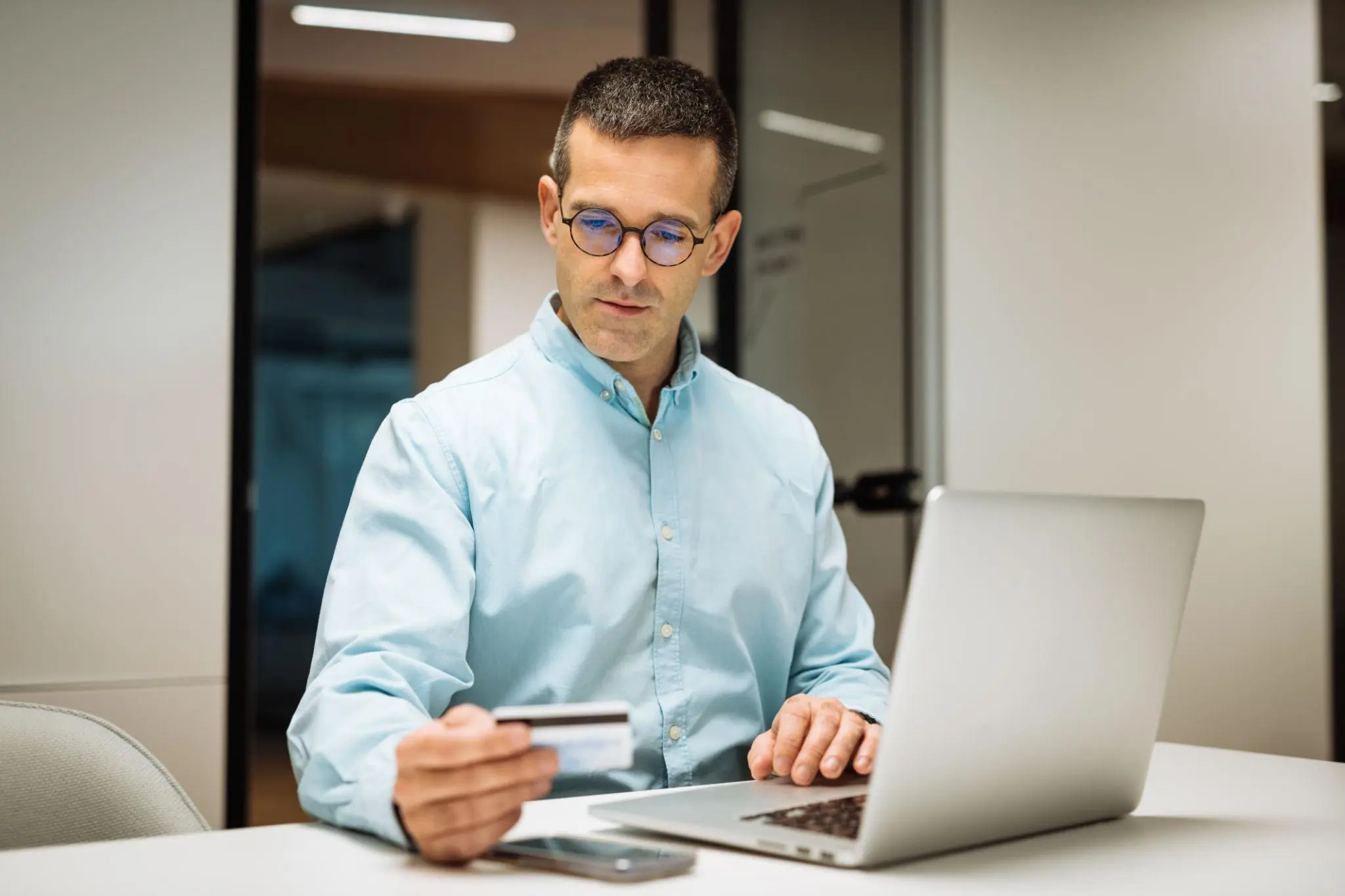 Entrepreneur holding a credit card at his laptop to pay for a reinstatement application Florida online.
