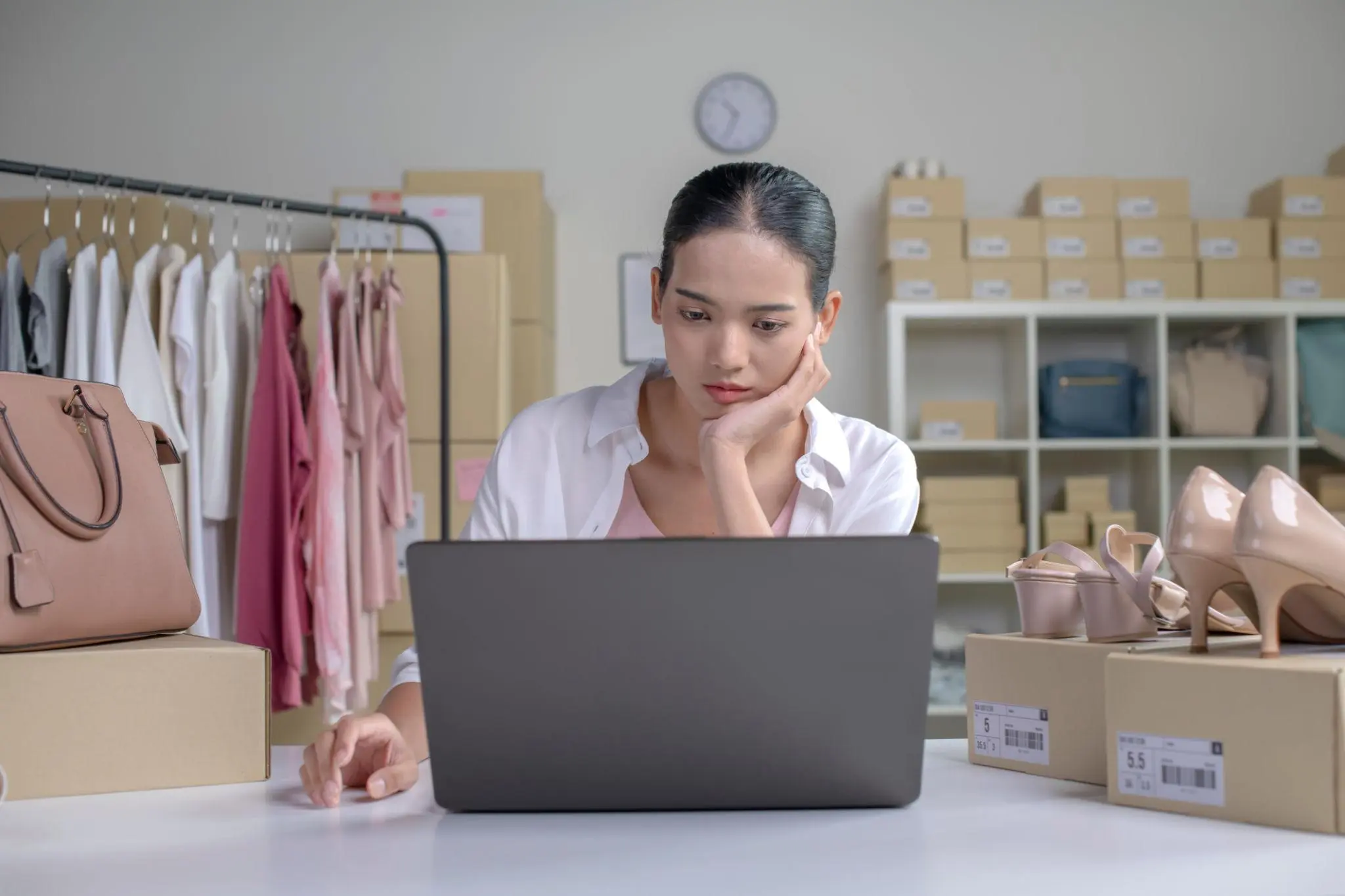 Pensive e-commerce expert at a laptop surrounded by inventory, checking the Florida LLC reinstatement timeline.