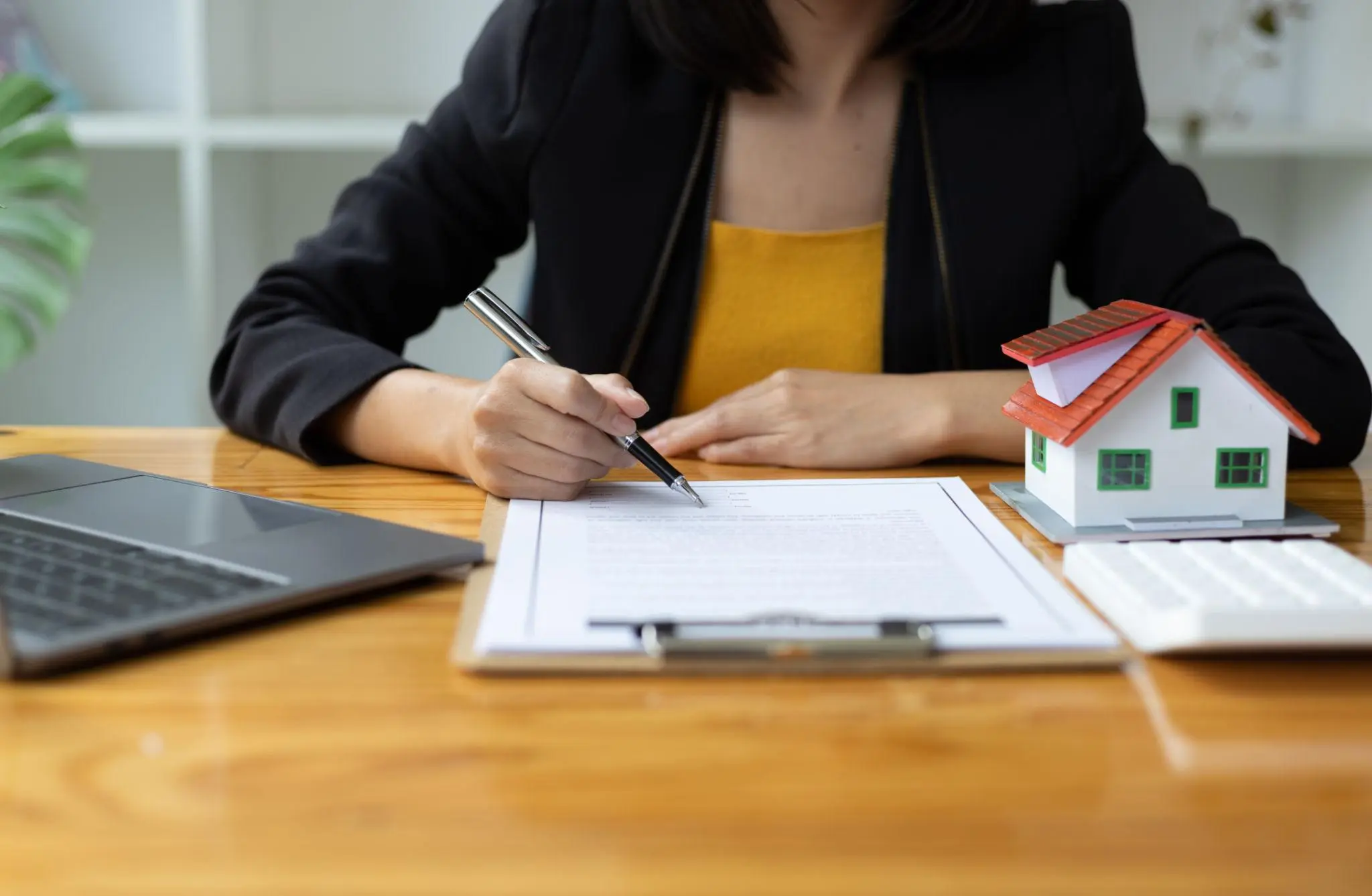 Real estate professional signing paperwork by a model house to resolve a Florida entity status inactive.